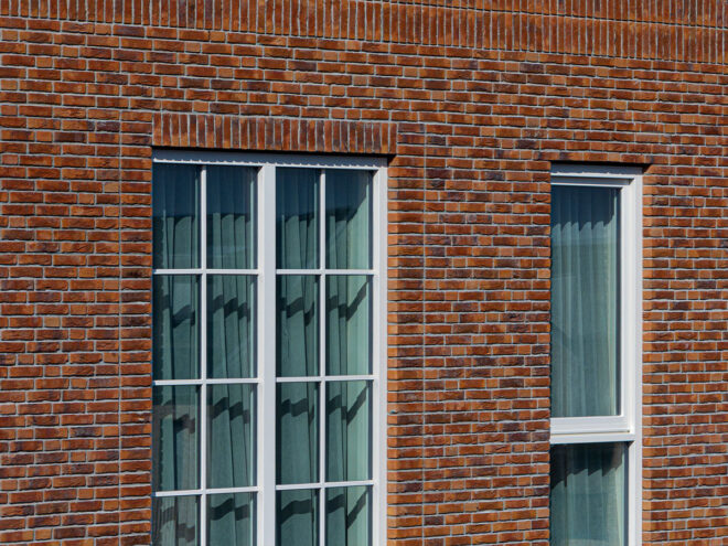 Houten kozijnen voor 47 woningen en 28 appartementen in Gouda, in de wijk Het Carré van Westergouwe. Foto van de de ramen van een woning.