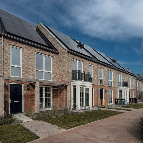 Houten kozijnen voor 47 woningen en 28 appartementen in Gouda, in de wijk Het Carré van Westergouwe. Foto van de voortuin van een aantal woningen.